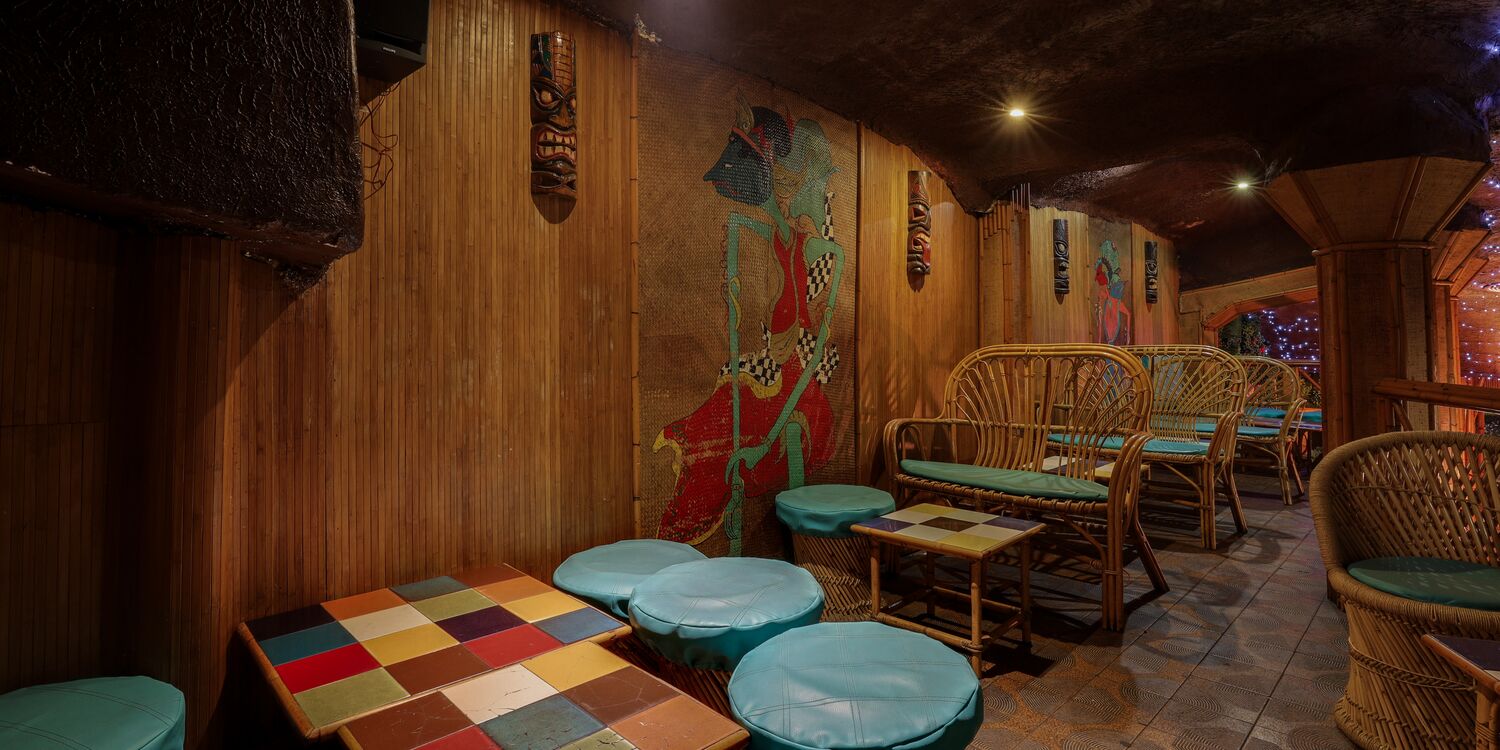 Mural tiki pintado a mano junto a la zona de sofás